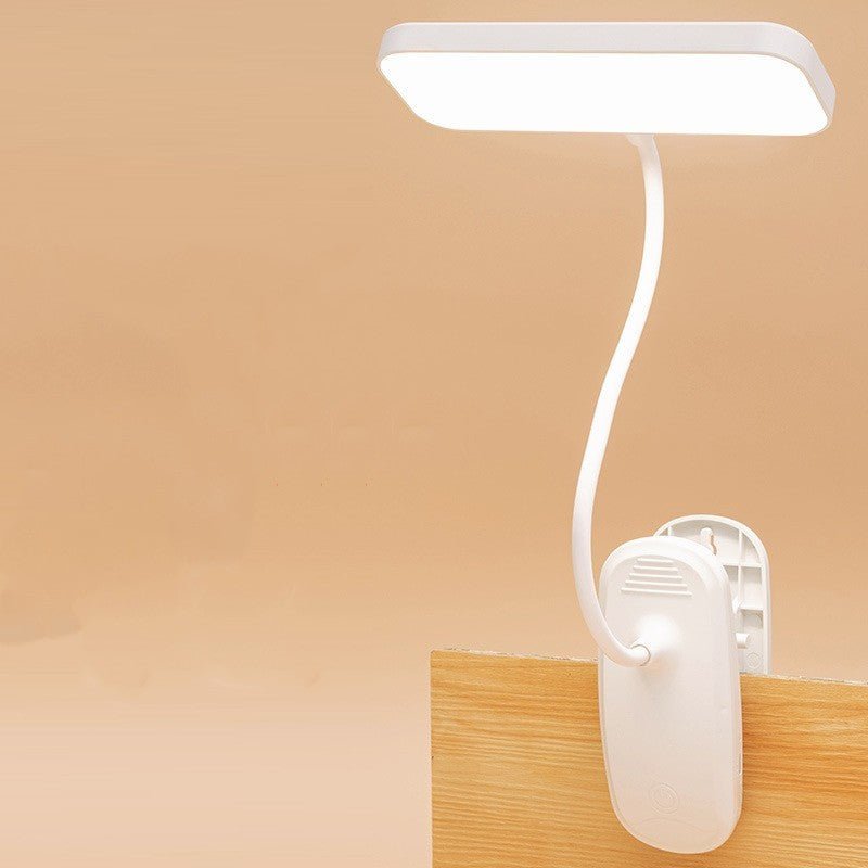 White flexible clip-on LED lamp attached to a wooden desk for study use
