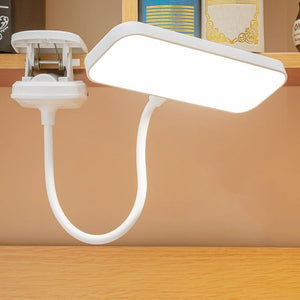 White flexible clip-on LED lamp attached to a wooden desk for study use