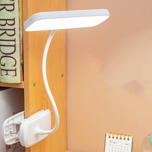 White flexible clip-on LED lamp attached to a wooden desk for study use