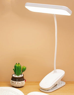 White flexible clip-on LED lamp attached to a wooden desk for study use